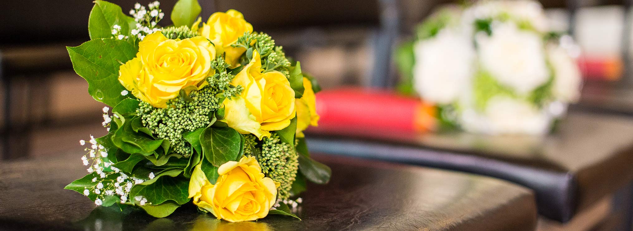 Ein Strauß aus gelben Rosen mit grünen Blättern, symbolisch für Trost und Erinnerung.