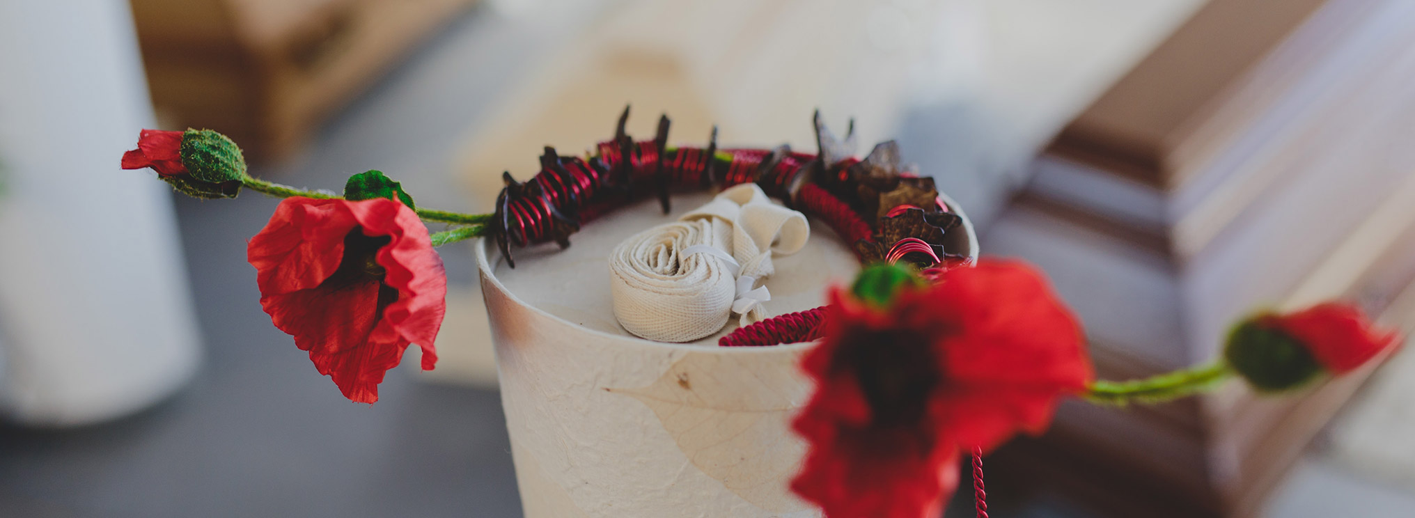 Eine rote Mohnblume als Dekoration auf einer Urne mit stilvollem Detail.